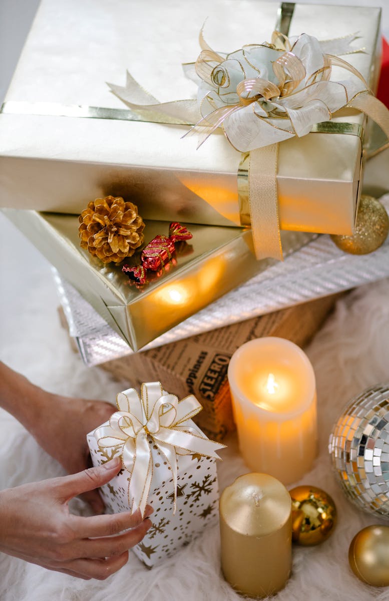 Stacked gifts with candles and ornaments create a cozy holiday atmosphere.