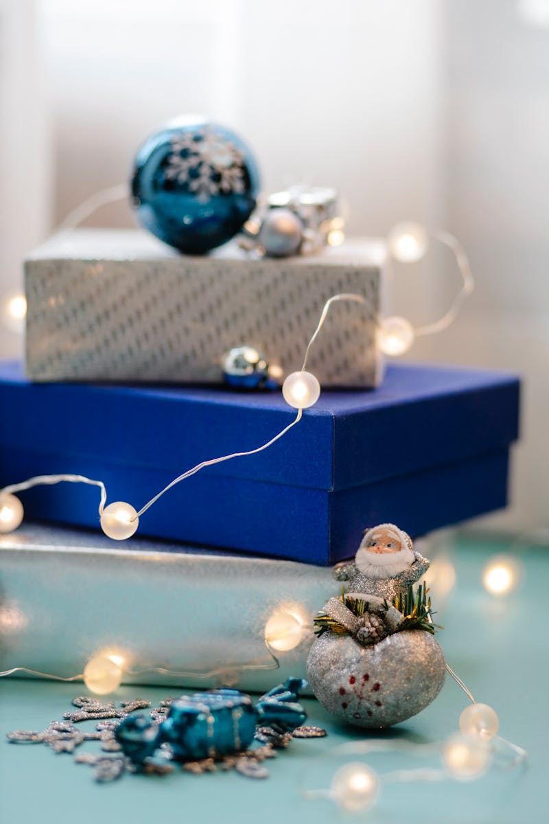Colorful holiday gift boxes with baubles and fairy lights for Christmas celebration.